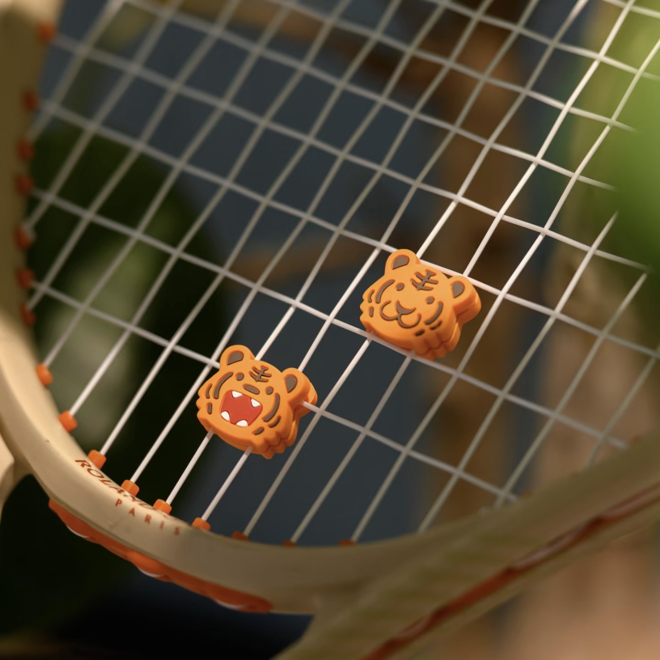 Custom tiger-shaped dampeners installed in a tennis racquet string bed