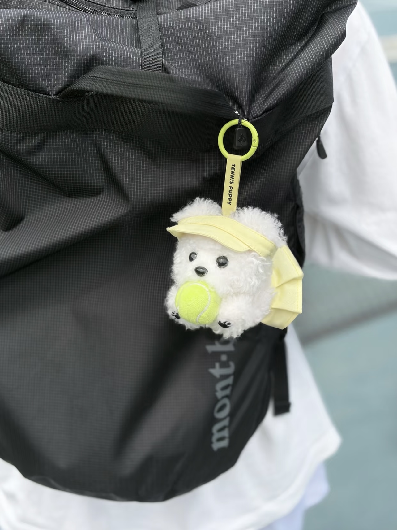 Tennis-themed plush dog charm attached to a sports bag