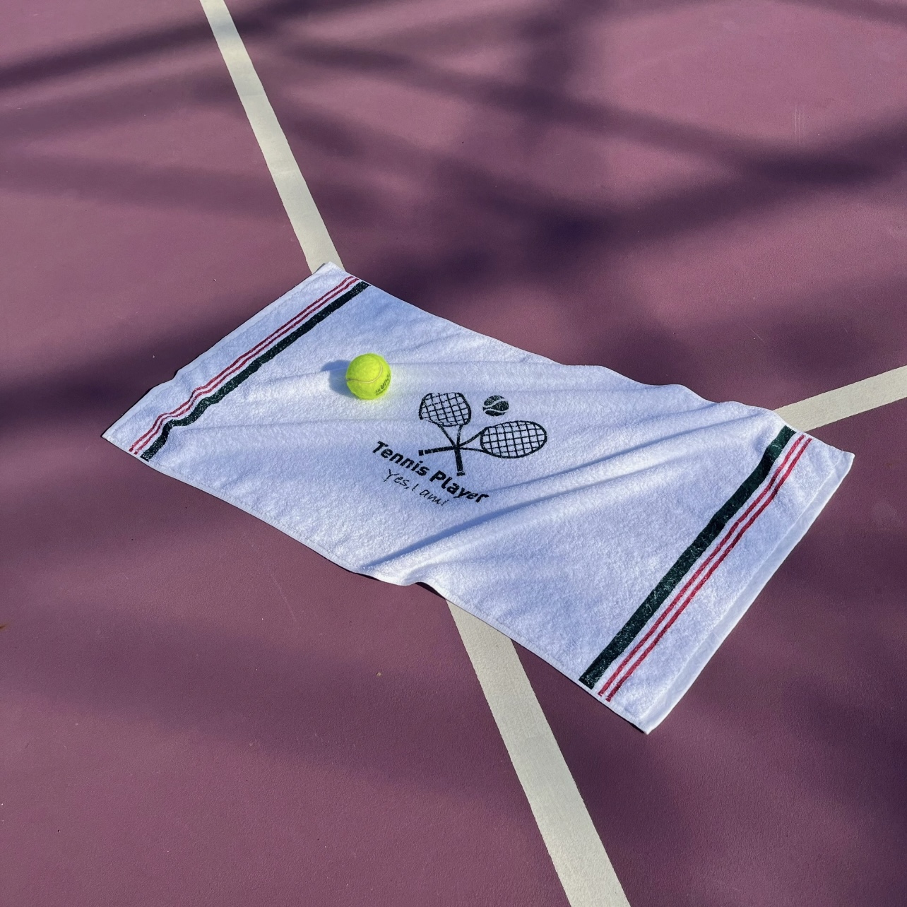 White custom tennis towel arranged on a court with a tennis ball