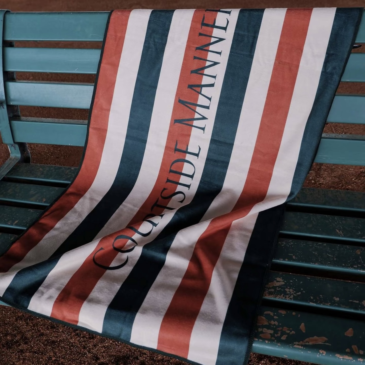 Striped custom court towel arranged on a courtside bench