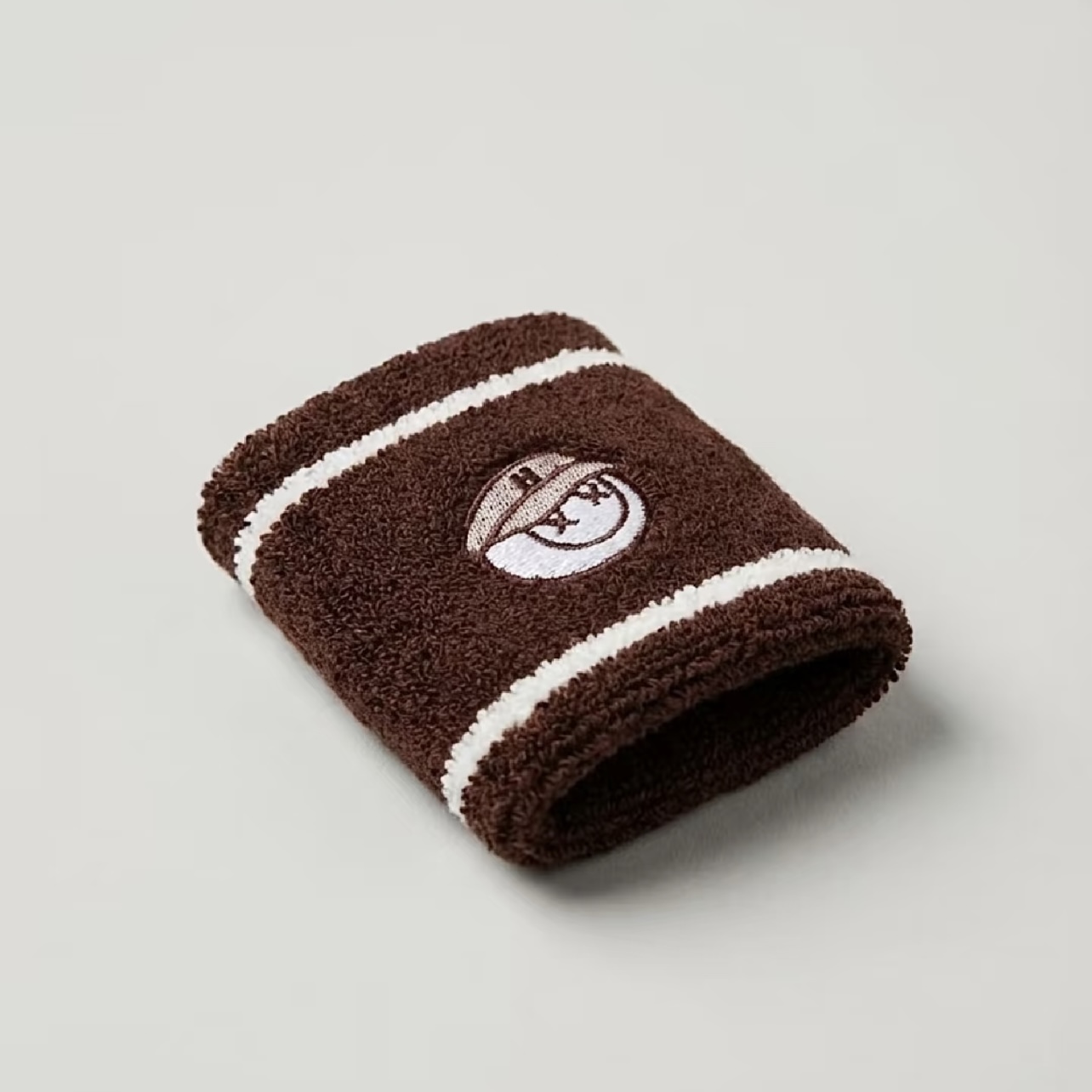 Brown and white striped wristband with embroidered circular logo