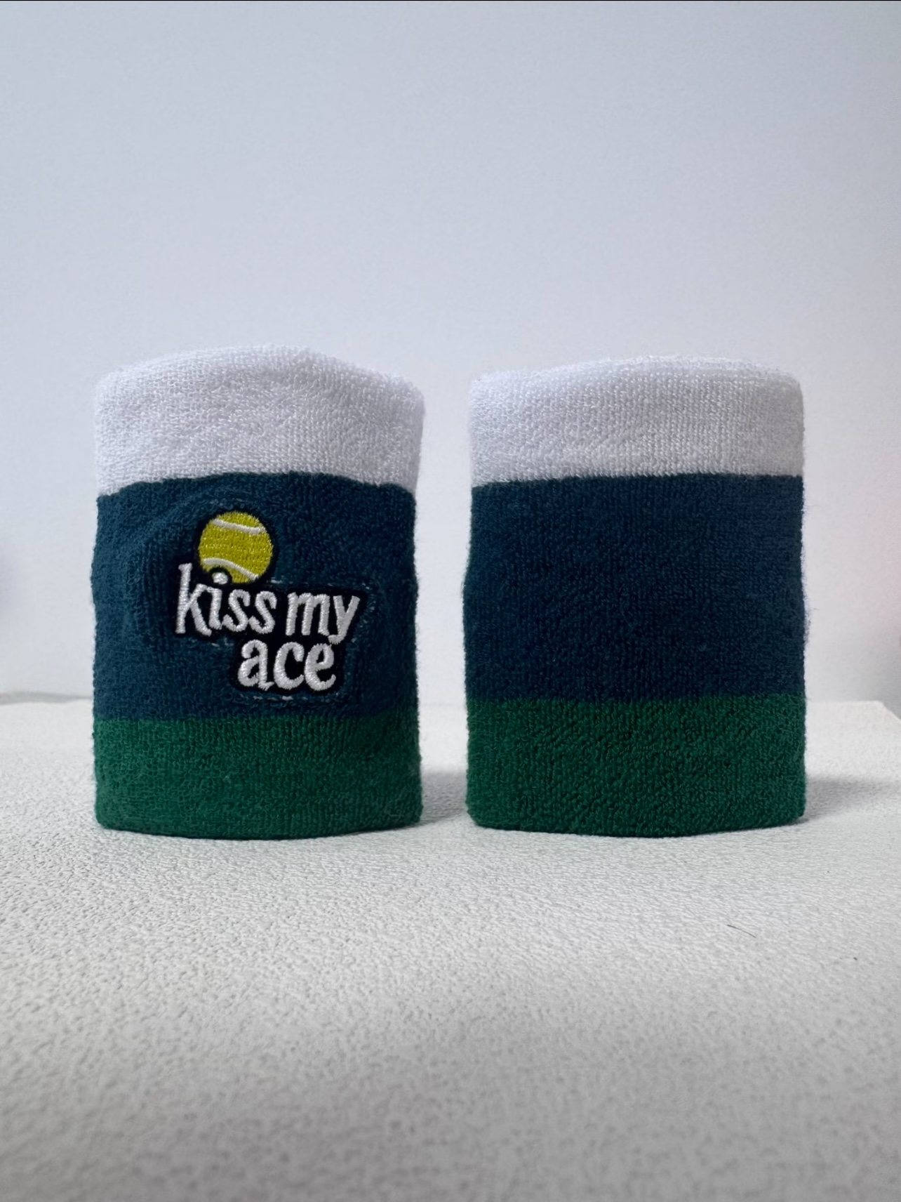 Green and white wristbands with embroidered tennis phrase